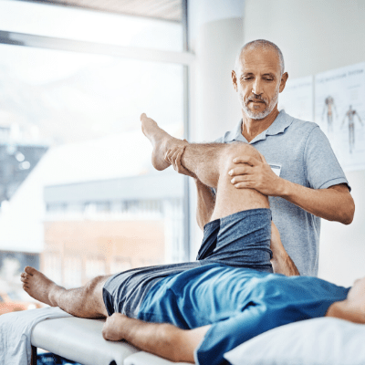 Physiotherapist treats man with injury in his clinic
